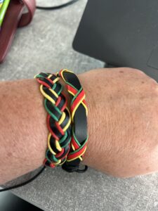 An arm wearing a wristband representing Rastafarian colours: black, red, green and gold.